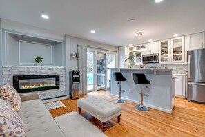A modern kitchen with a built-in microwave, stainless steel refrigerator, and a bar area with stools.