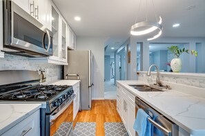 A modern kitchen with a stove, microwave, refrigerator, and a sink with a vase of flowers.
