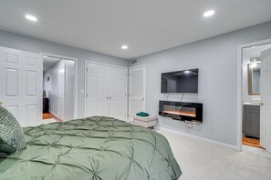 A bedroom with a bed, a TV mounted on the wall, and a fireplace.