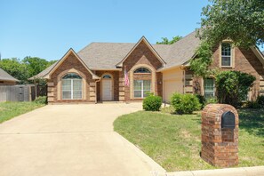A two-story house with a brick facade, a front garage, and a well-maintained lawn. - Spacious 5-bedroom house with AC -  Workers Welcome 10 Beds (Abilene)