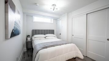 A bedroom with a bed, a nightstand, a window, and a door.