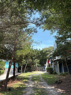 A pathway leading through a residential area with houses on either side, surrounded by trees.