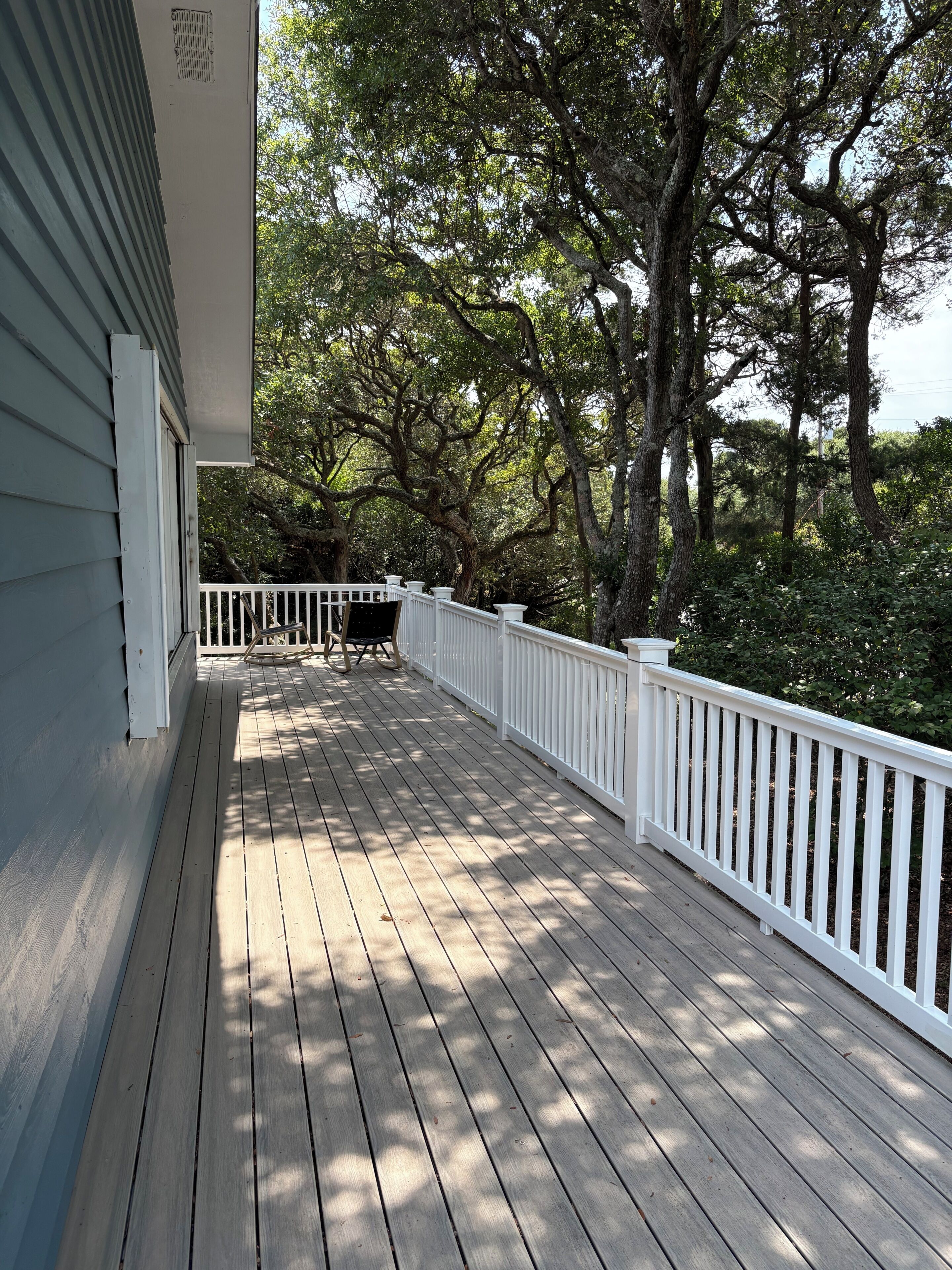 Une terrasse en bois avec une balustrade blanche, un banc et une table.
