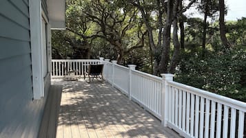 Une terrasse en bois avec une balustrade blanche, un banc et une table.