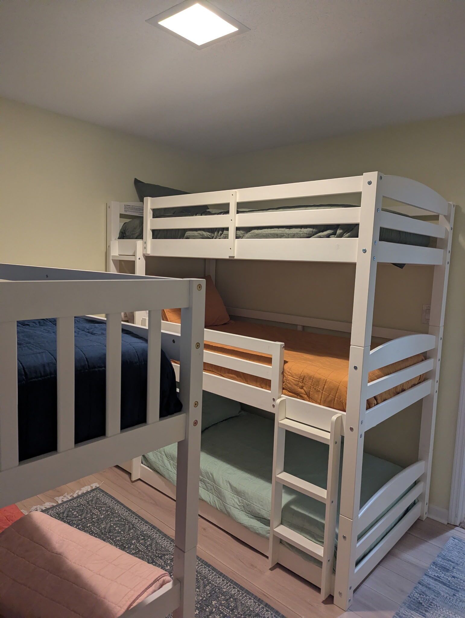 A bunk bed with a ladder and a small table in a room with a light-colored floor and walls.