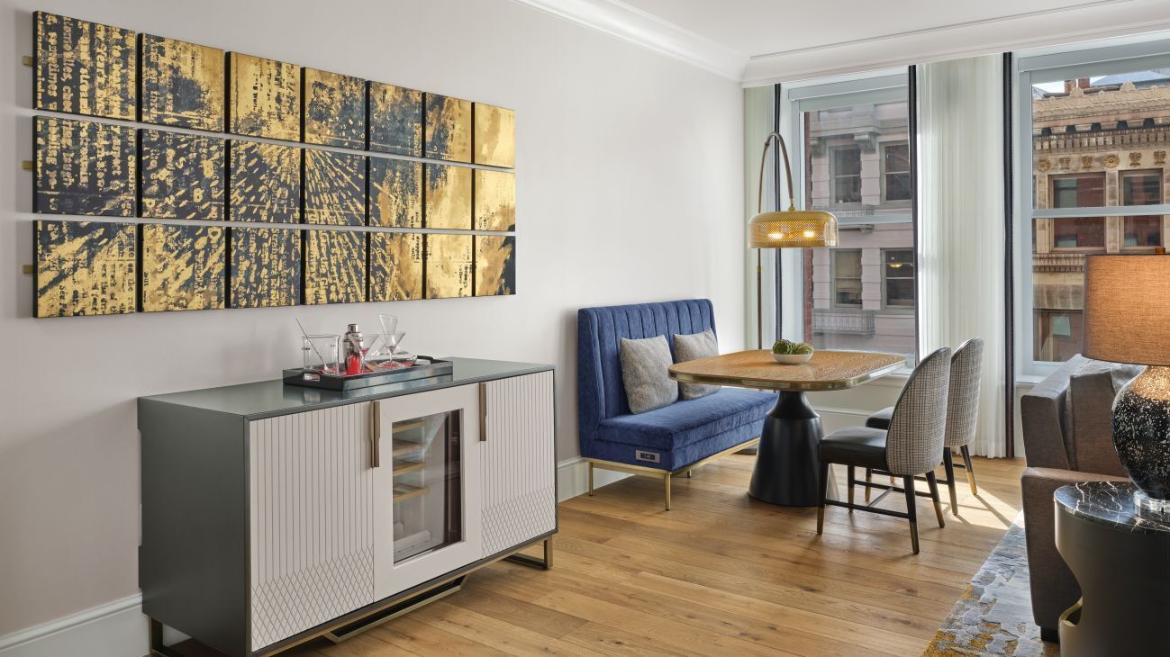 Un salon moderne avec un canapé, une table à manger et un grand tableau abstrait accroché au mur.