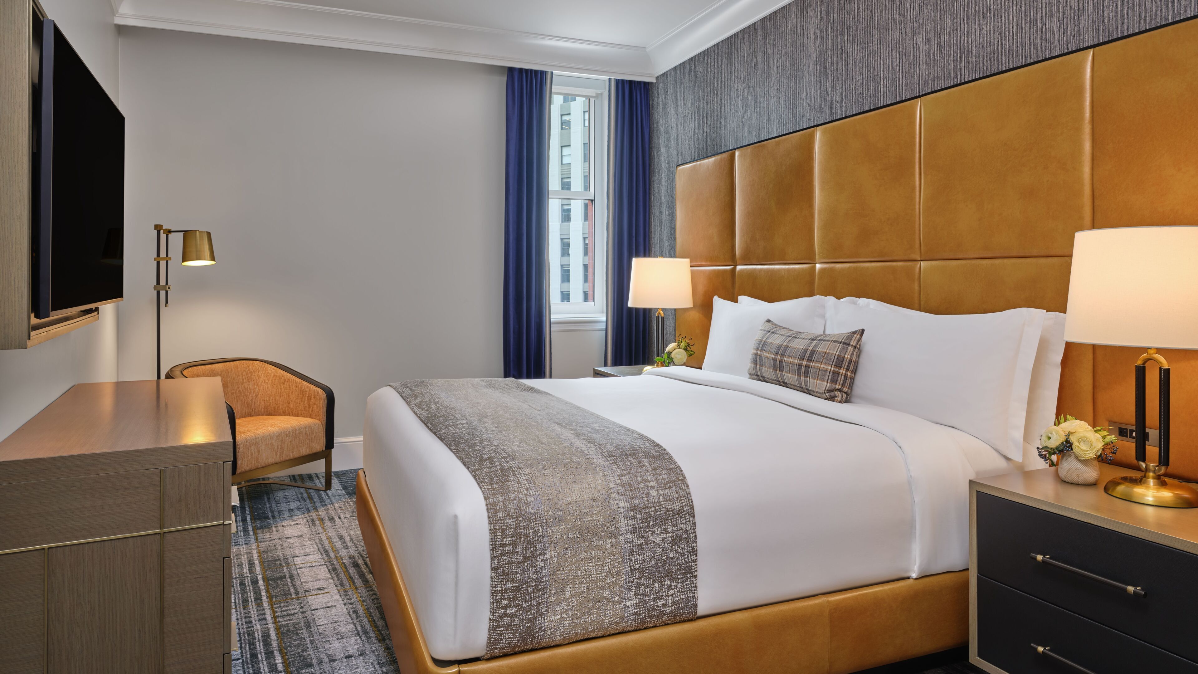 Une chambre d’hôtel comprenant un lit, des tables de chevet, un bureau, une chaise et un téléviseur.