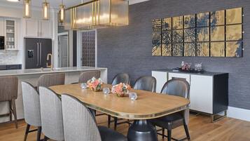 A modern kitchen with a central island, a dining area with a wooden table and chairs, and a large abstract art piece on the wall.