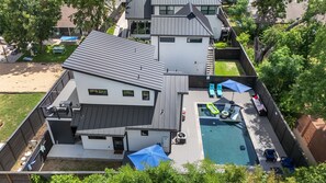 A modern house with a swimming pool, outdoor seating, and a fenced yard. - Central Austin Cozy Retreat, 3 Bedroom, 2.5 bath, Large Outdoor Pool & Spa (Austin)
