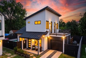 Ein modernes, zweistöckiges Haus mit überdachter Terrasse und Garage.