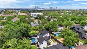 A residential area with houses, a swimming pool, and a city skyline in the background. - Central Austin Cozy Retreat, 3 Bedroom, 2.5 bath, Large Outdoor Pool & Spa (Austin)