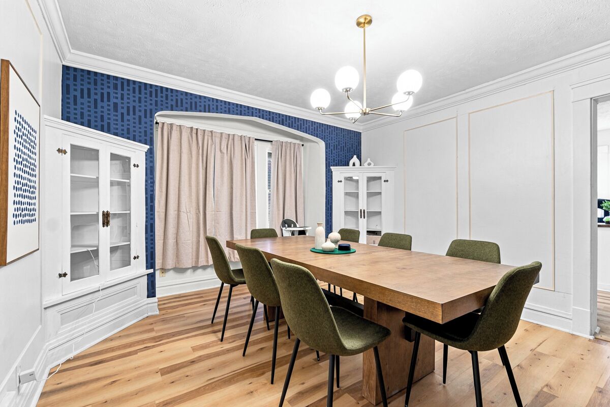 A dining area with a wooden table, green upholstered chairs, and a chandelier.