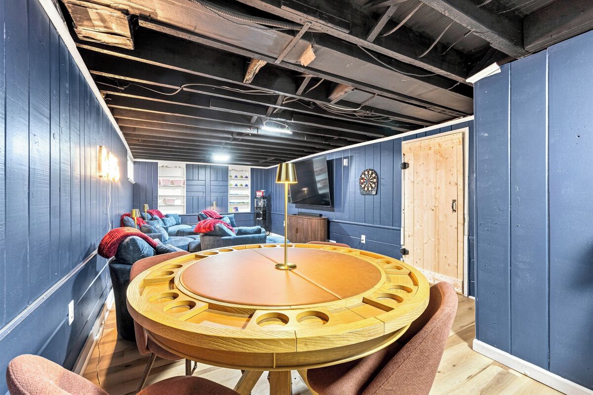 A room with a round wooden table, sofas, and a television.