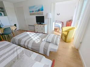 Ein Hotelzimmer mit zwei Betten, einem Fernseher, einem Schreibtisch und einem Stuhl.