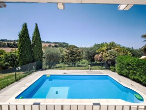 Una piscina rectangular amb superfície d'aigua blava cristal·lina, envoltada per un terra solcat i una tanca metàl·lica.