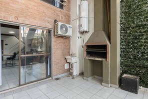 A brick building with a glass door entrance, a BGH air conditioning unit, a white sink, and a brick oven. - Spacious Duplex by Don Julio (Buenos Aires)