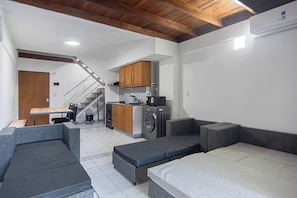 A compact living space with a kitchenette, a dining area, and a staircase leading to an upper level. - Spacious Duplex by Don Julio (Buenos Aires)