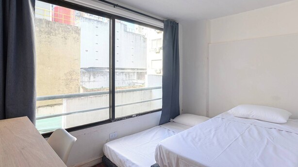 Pieni hotellihuone, jossa on yksi huone, sänky, työpöytä ja ikkuna.