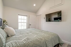 A bedroom with a bed, a window, a door, and a mounted shelf. - 66 Cottage on Historic Rt 66 -Starlit Stone (El Reno)