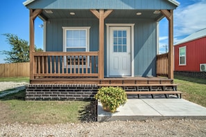A small house with a porch, two doors, a small garden, and a gravel driveway. - 66 Cottage on Historic Rt 66 -Starlit Stone (El Reno)