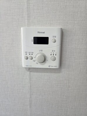 Ein weißer Rinnai-Warmwasserbereiter mit digitaler Anzeige, Bedienelementen und einer Modellnummer.