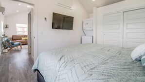 Ein Schlafzimmer mit einem Bett, einem Fernseher, einem Kleiderschrank und einer Tür zu einem anderen Raum.