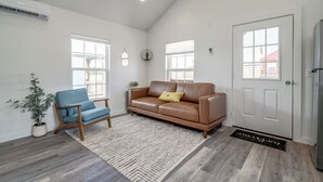Ein geräumiges Wohnzimmer mit einem braunen Ledersofa, einem blauen Sessel und einem Holztisch.