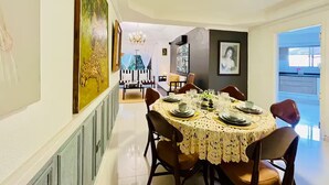 A dining area with a round table set for six, flanked by chairs, and a large painting on the wall.