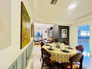 A dining area with a round table set for six, flanked by chairs, and a large painting on the wall.