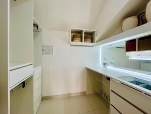 A modern kitchen with white cabinetry, a built-in oven, and a glass-fronted display case. - Dúplex Premium - Piscinas, Jacuzzi & Sauna (Santa Cruz de la Sierra)