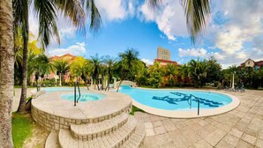 A resort with two circular pools, palm trees, and a building in the background.