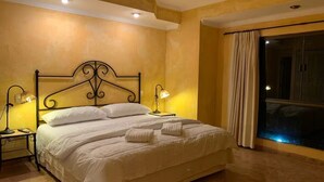A hotel room with a large bed, two bedside lamps, a view of the night sky through a window, and a curtain.