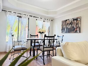 A dining area with a table and chairs, a sofa, and a painting on the wall. - Spa Retreat - Sauna + Resort Style Amenities (Santa Cruz de la Sierra)