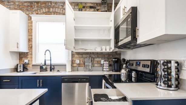 Una cucina moderna con mobili bianchi, una lavastoviglie in acciaio inox e un forno integrato.
