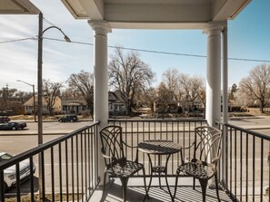 Ein Balkon mit Metallgeländer, drei Stühlen und einem kleinen Tisch.