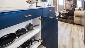 Una cucina moderna con un armadietto blu, un fornello con pentole e un'area pranzo con un divano e una sveglia al muro.