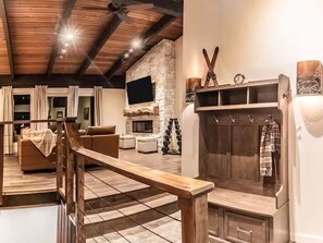 A modern living room with a fireplace, a wooden bench, and a stone wall. - 4BR Canyon Lodge Base - Shuttle, Hot Tub & Room for 10 (Mammoth Lakes)