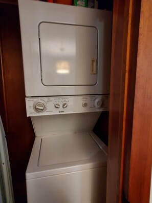 A stacked washer and dryer unit with control knobs and a door. - Goodyear Lake Boathouse - charming historic cottage overlooking the water (Oneonta)