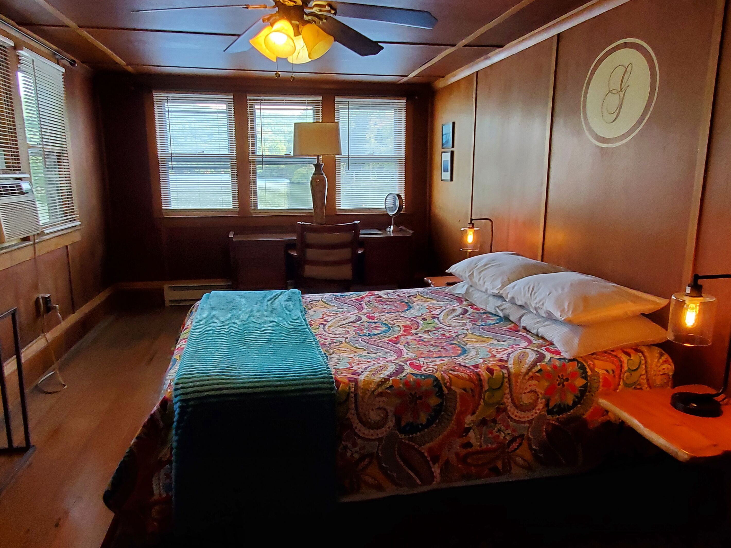 A bedroom with a bed, bedside table, lamp, and a ceiling fan.
