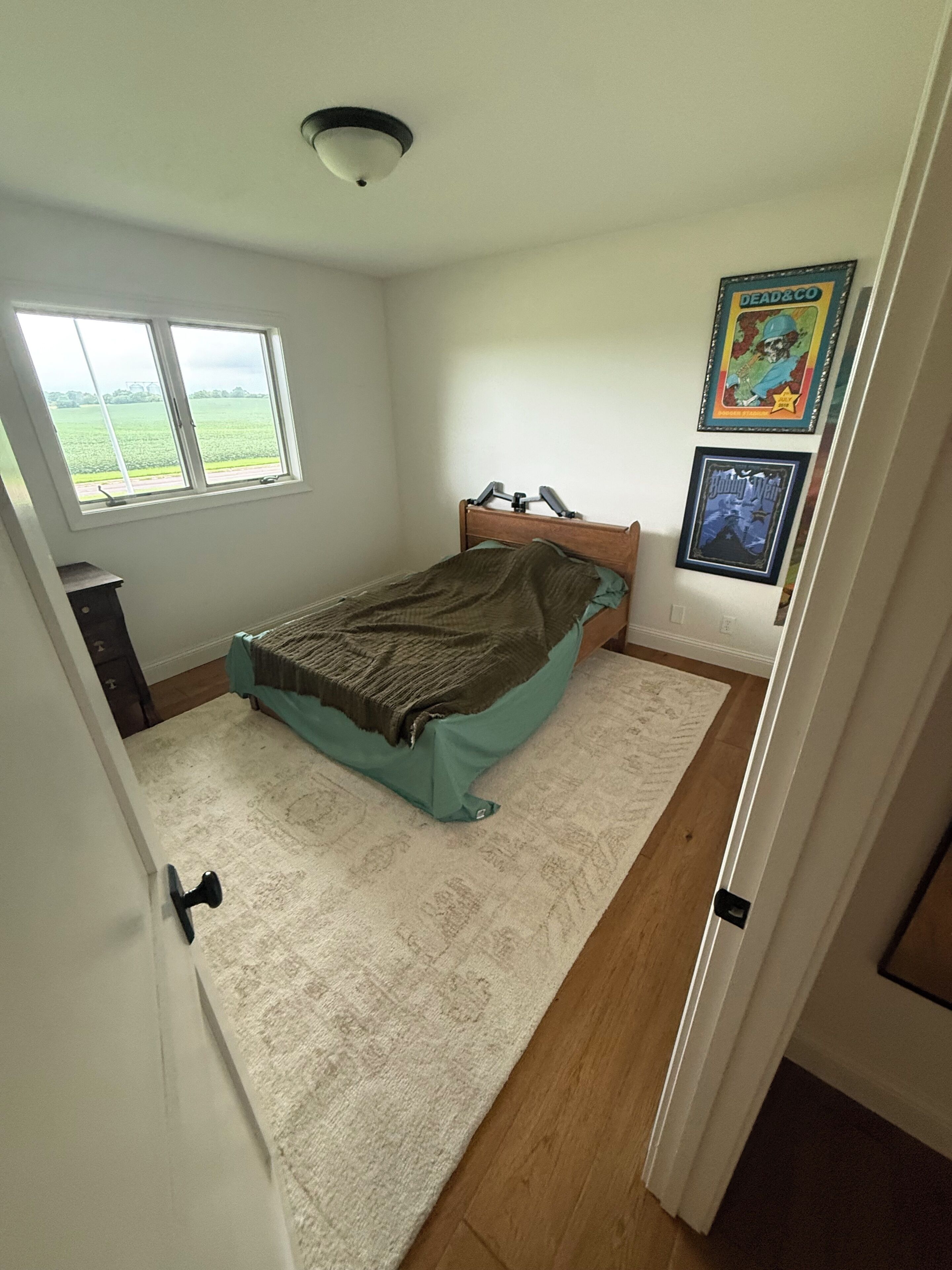Ein Schlafzimmer mit einem Bett, einem Fenster, einer Tür und einer Wand mit zwei gerahmten Bildern.