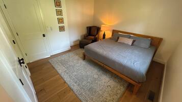 Un dormitorio con cama, una silla, un tapete y un ventilador de techo.