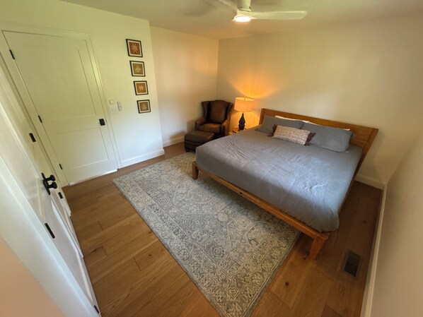 A bedroom with a bed, a chair, a rug, and a ceiling fan.