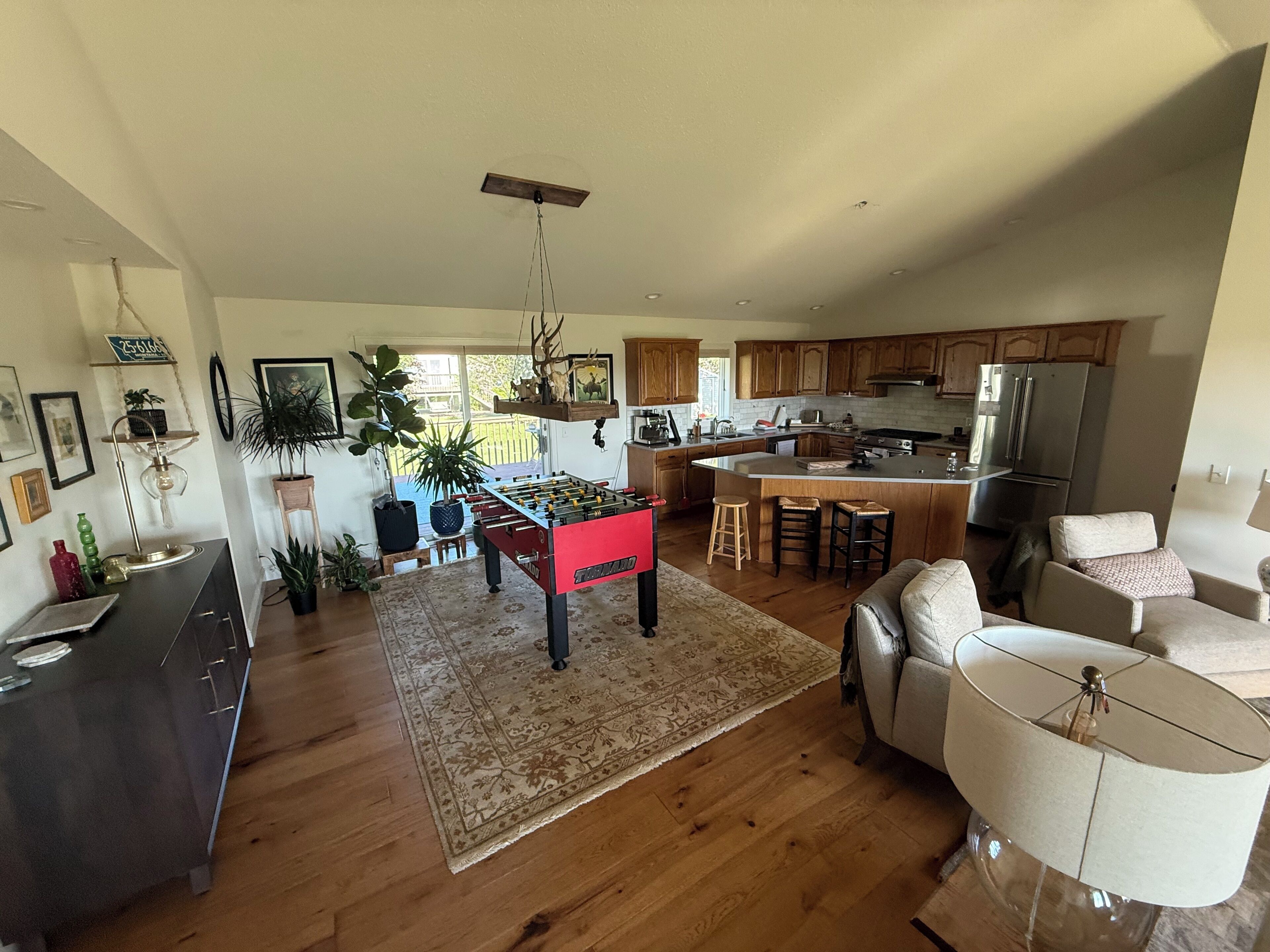 A spacious living area with a foosball table, a kitchen with modern appliances, and a dining area with a large island.