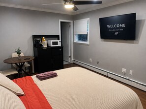 A modern bedroom with a bed, a small table, a microwave, and a TV displaying 'WELCOME'. - BED AND BATH W/D IN BUILDING /Private Entrance (Stamford)