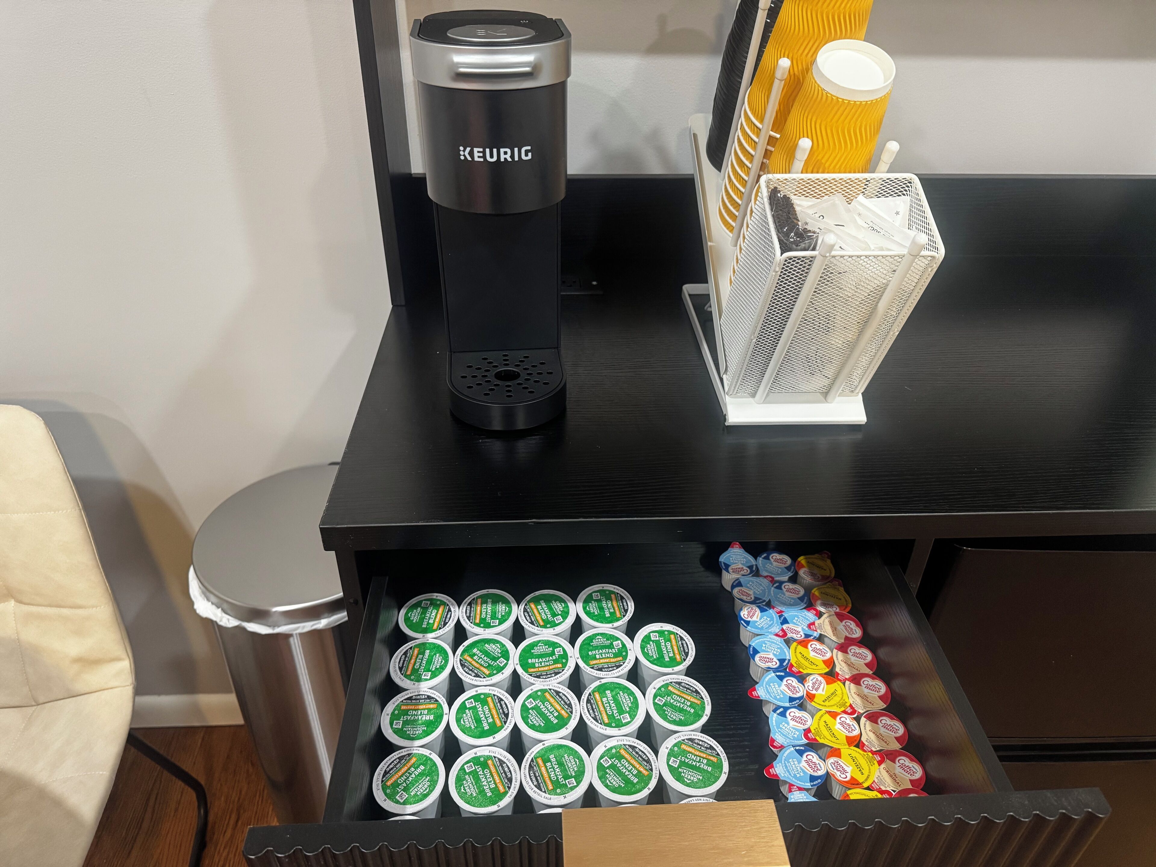 A coffee machine and a drawer with various coffee pods.
