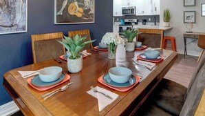 A dining area with a wooden table set for four, surrounded by chairs.