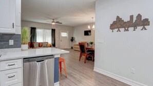 A modern kitchen with a dishwasher, a dining area with a table and chairs, and a wall with a Tampa cityscape decal.