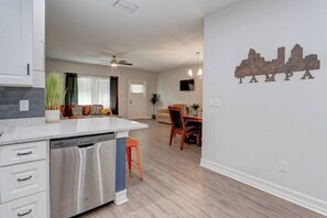 Una cocina moderna con lavavajillas, un comedor con mesa y sillas, y una pared con un adhesivo del paisaje urbano de Tampa.
