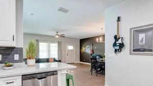 Eine moderne Küche mit Geschirrspüler, ein Essbereich mit Tisch und Stühlen sowie eine Gitarre an der Wand.
