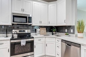 A modern kitchen with white cabinets, a stainless steel microwave, an oven, and a dishwasher. - ♫Rock n’ Roll Bungalow♫Balcony☞3 King Beds ☜ (Tampa)